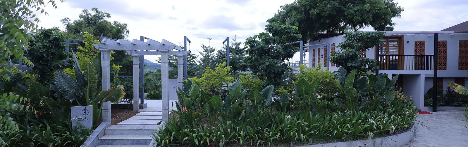 Landscaped entrance with steps and greenery near rooms at Trishvam Symphony, Krishnagiri.