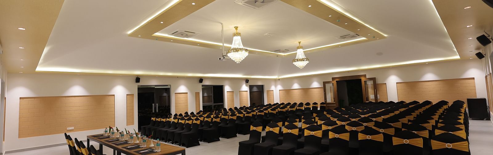 A boardroom with neatly arranged chairs with warm lighting at Trishvam Symphony, Krishnagiri