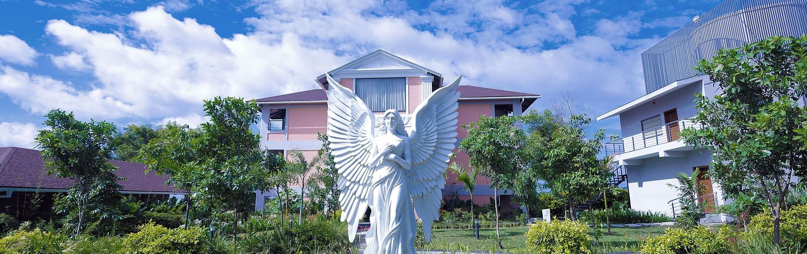 White angel sculpture in landscaped garden with villas in the background at Trishvam Symphony, Krishnagiri.