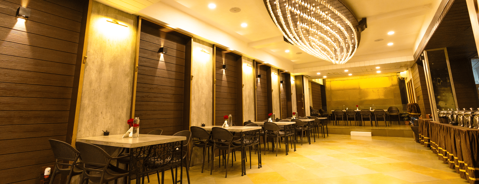 An indoor dining area with dining tables, chairs, and ceiling lights at Hotel Seagull Digha.