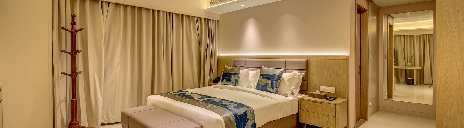 A hotel room with a bed, a bench, and a view of the bathroom - The SSK Solitaire Boutique Hotel & Spa, Gangapur Road - Nashik