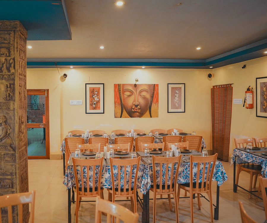 A dining space featuring tables and chairs arranged throughout, with photo frames on the wall and a large pillar in the room