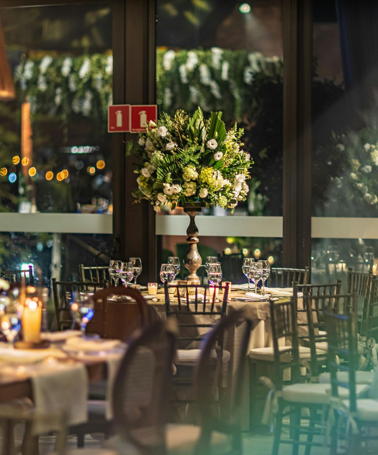 An overview of a beautiful banquet hall with tables decorated with shiny glassware and flowers.