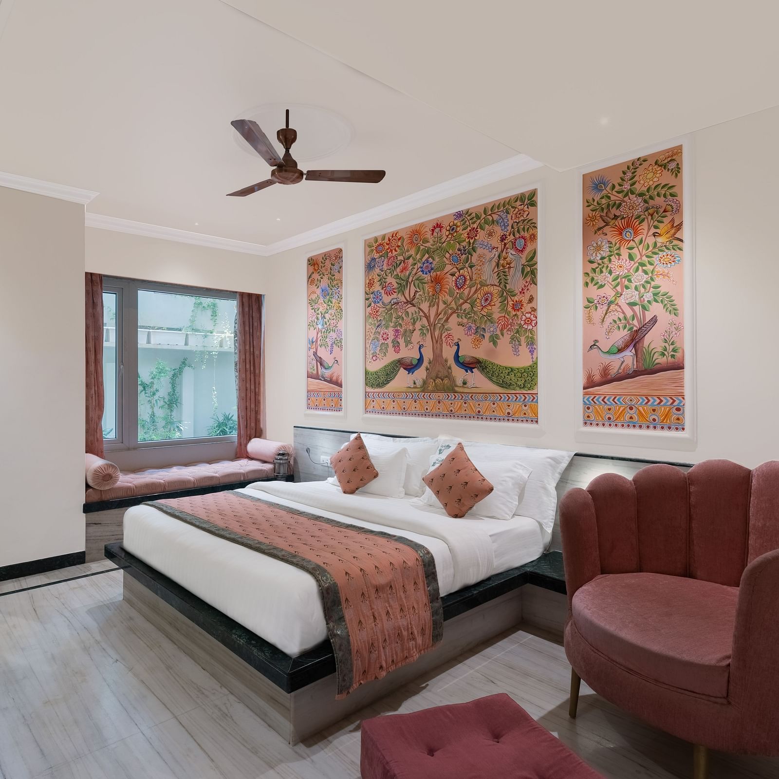 A spacious bedroom at Panna Vilas Palace, featuring a wooden table, cushioned furniture, warm lighting, and a large window