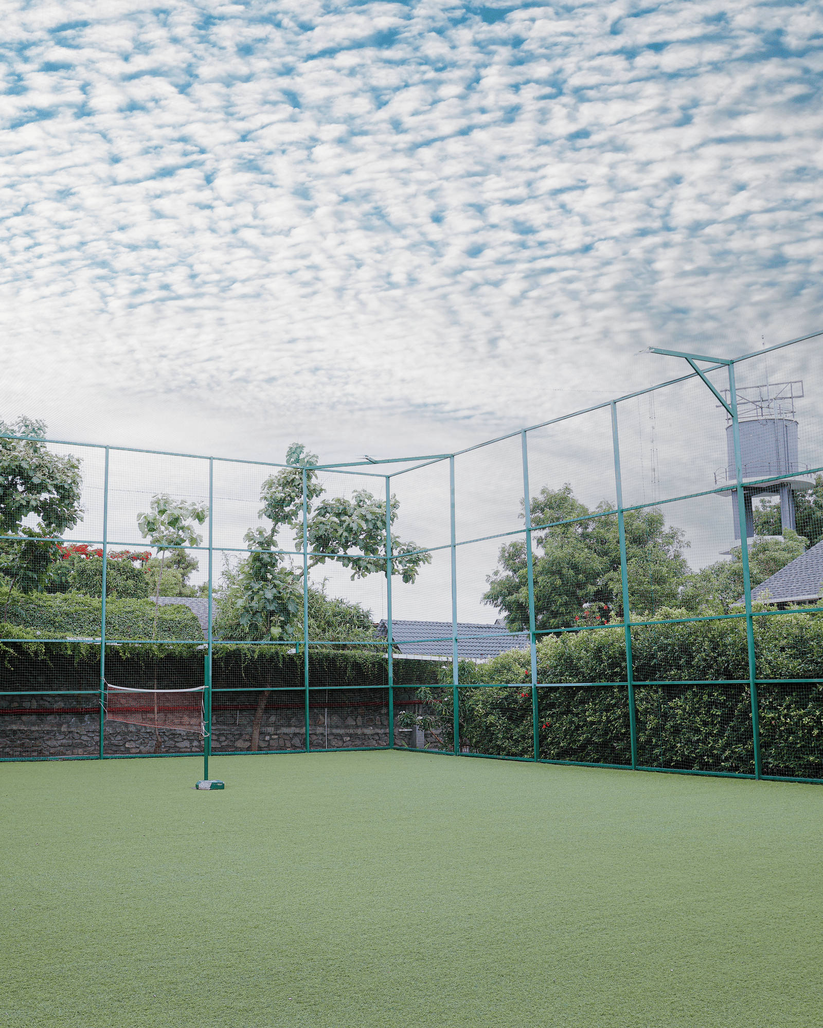 Outdoor tennis court at Darza Resort surrounded by landscaped gardens and protective netting, offering guests a well-maintained recreational facility for enjoyable games and active leisure.