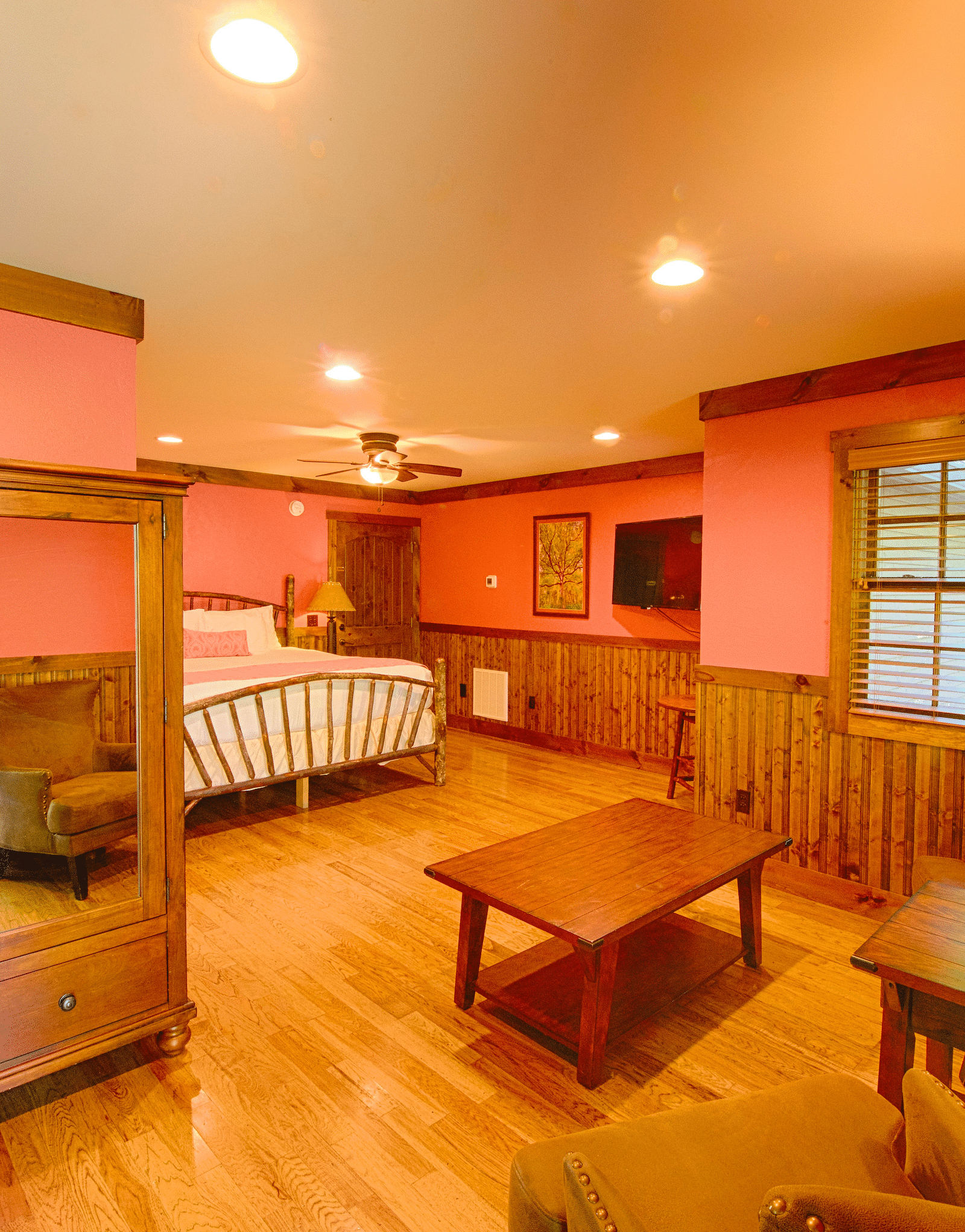 corner view image of a bedroom with a wardrobe and common seating area and a double bed at the far end - Historic Tapoco Lodge