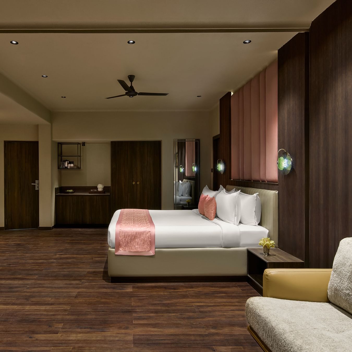 Junior Suite with a large bed, a sofa, and a television, featuring warm lighting and wooden accents at DGV Resort by Treat, Silvassa.