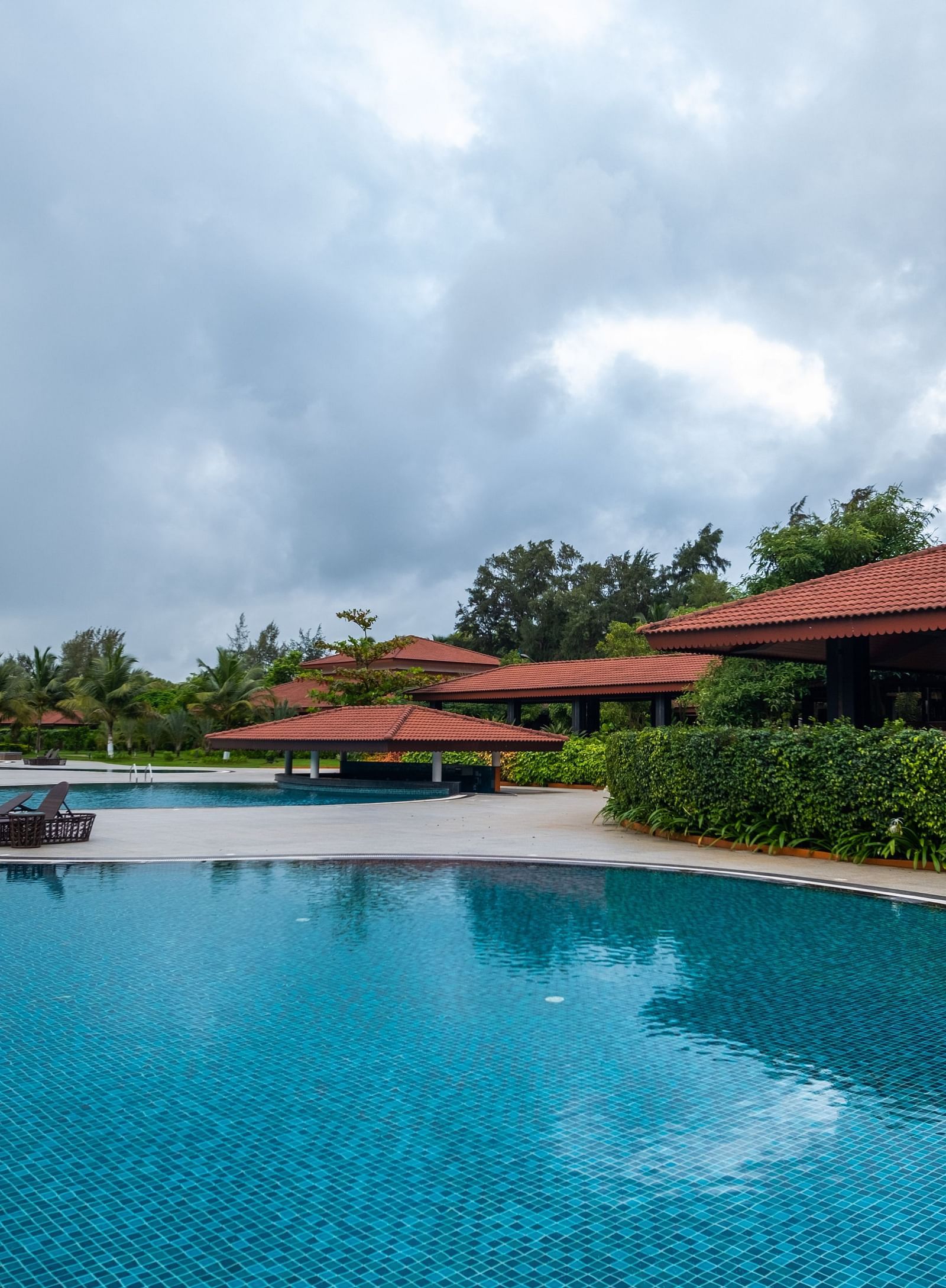 An overview of the swimming pool inside gamyam retreat with trees in the background