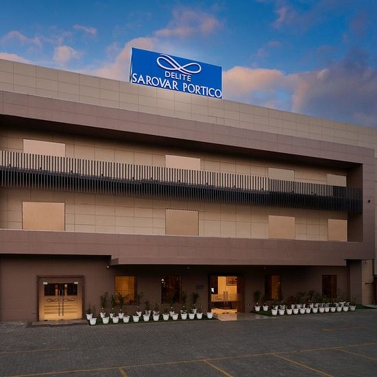 A facade image of a hotel with a sign board of the hotel name on the top