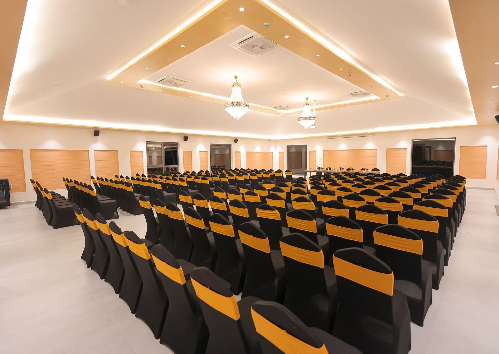 Spacious seminar hall at Trishvam Symphony, Krishnagiri, with black and yellow cushioned chairs arranged theatre-style.