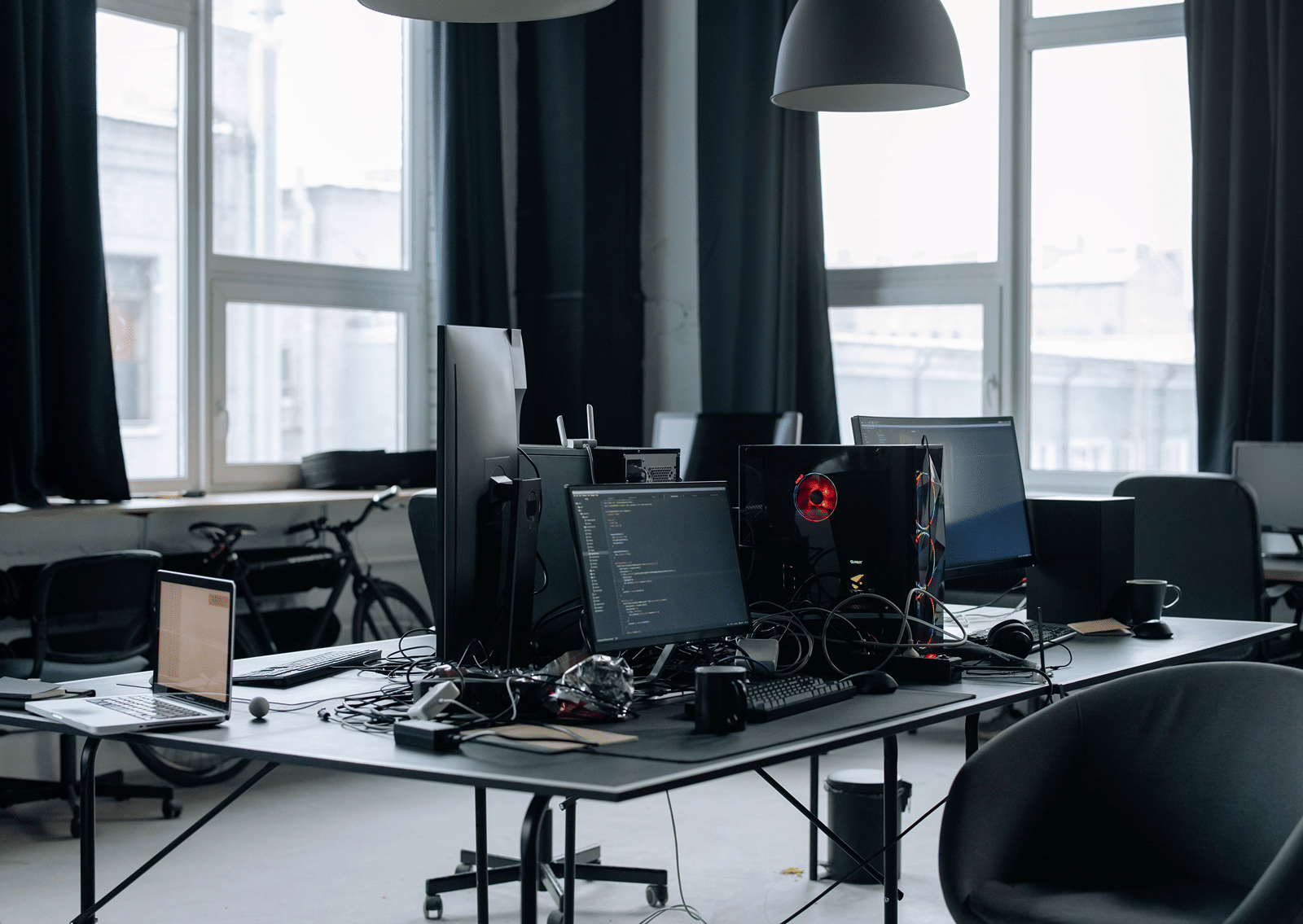 Interior of a modern open-plan office space featuring desks, computer monitors, and large windows.