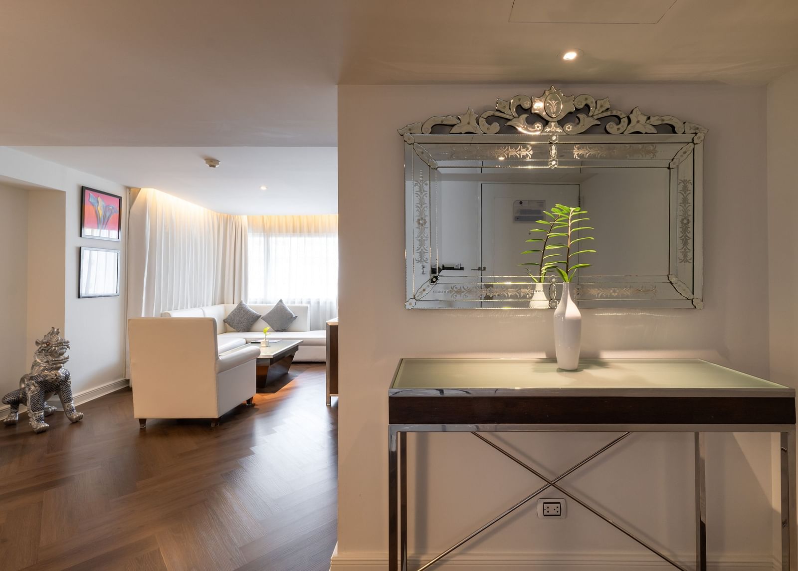 An overview of a room with a table having a vase and a mirror on the wall - Night Hotel Bangkok.