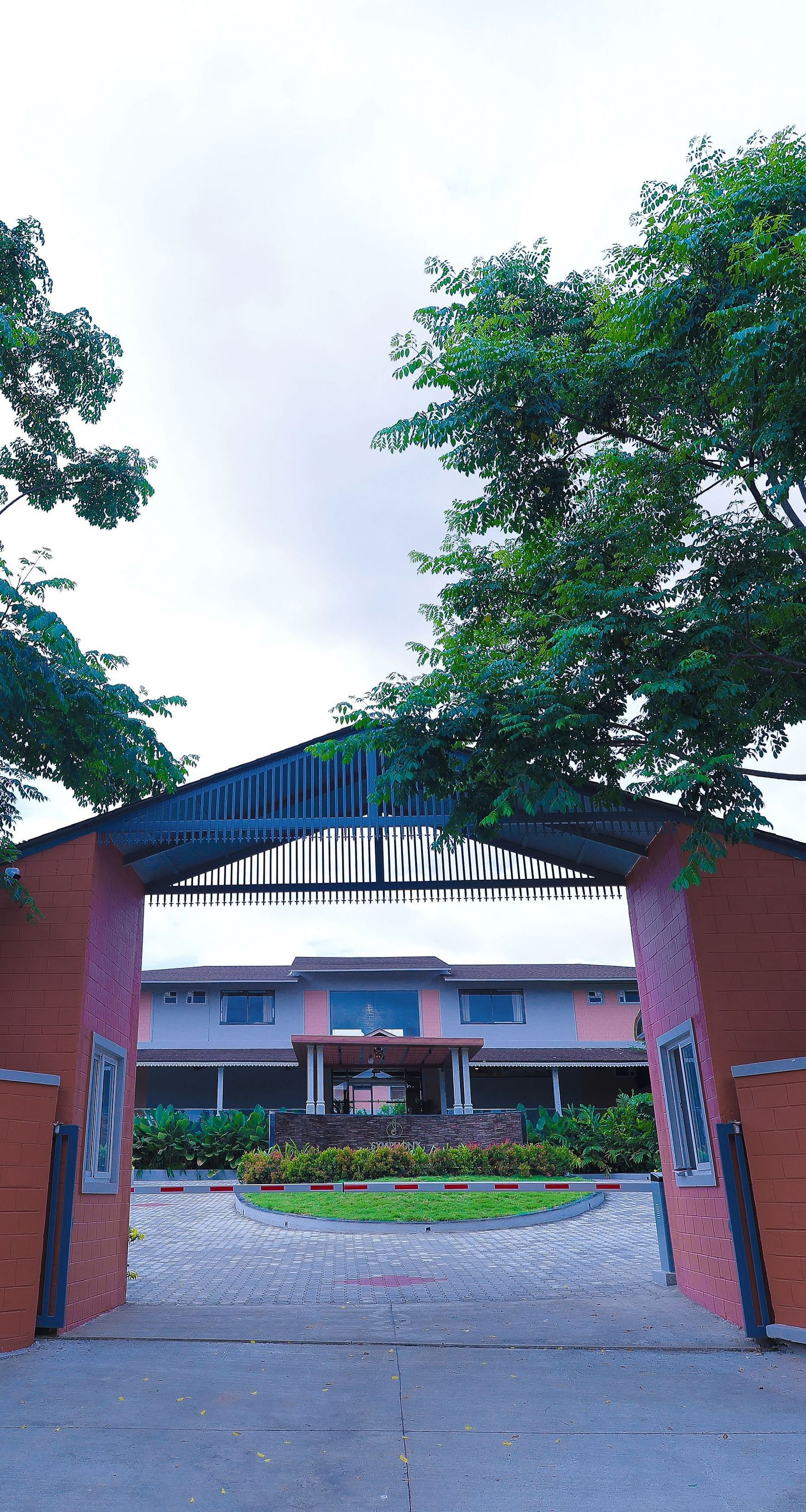 Entry gate structure surrounded by trees and walls at Trishvam Symphony, Krishnagiri.