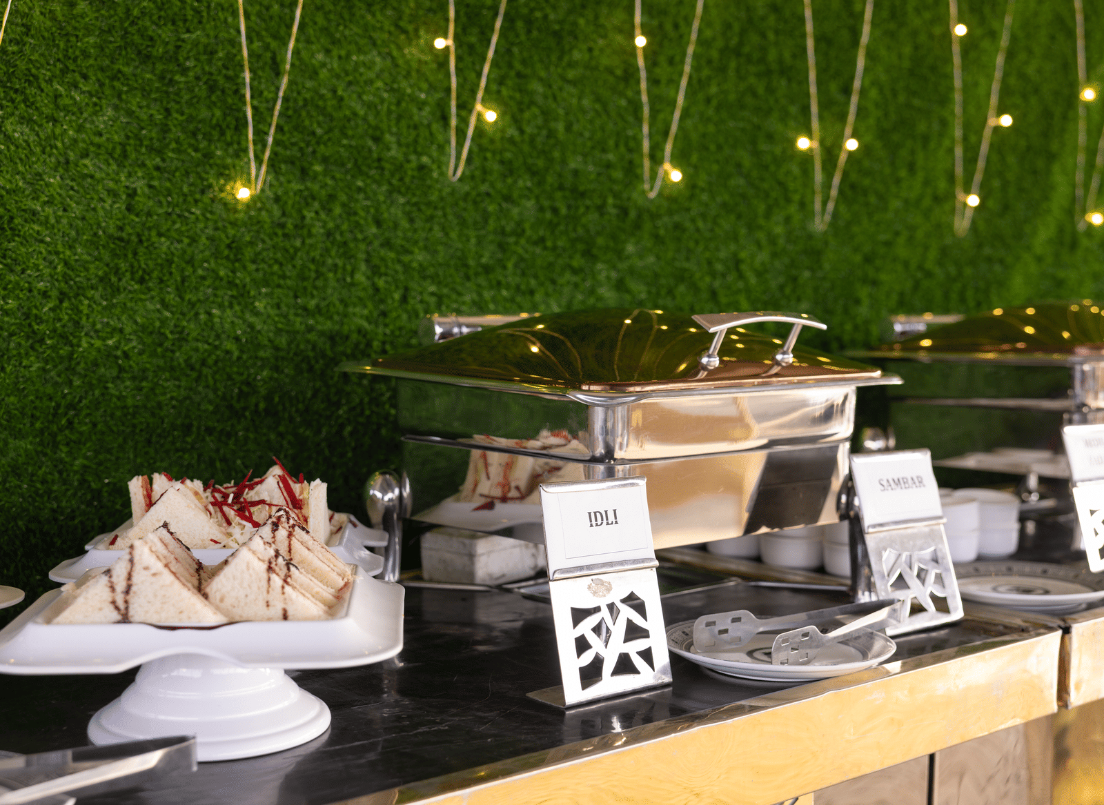 Shot of a buffet setup with food items and a decorative wall background at Pravasa Stay Luv Kush, Indore.