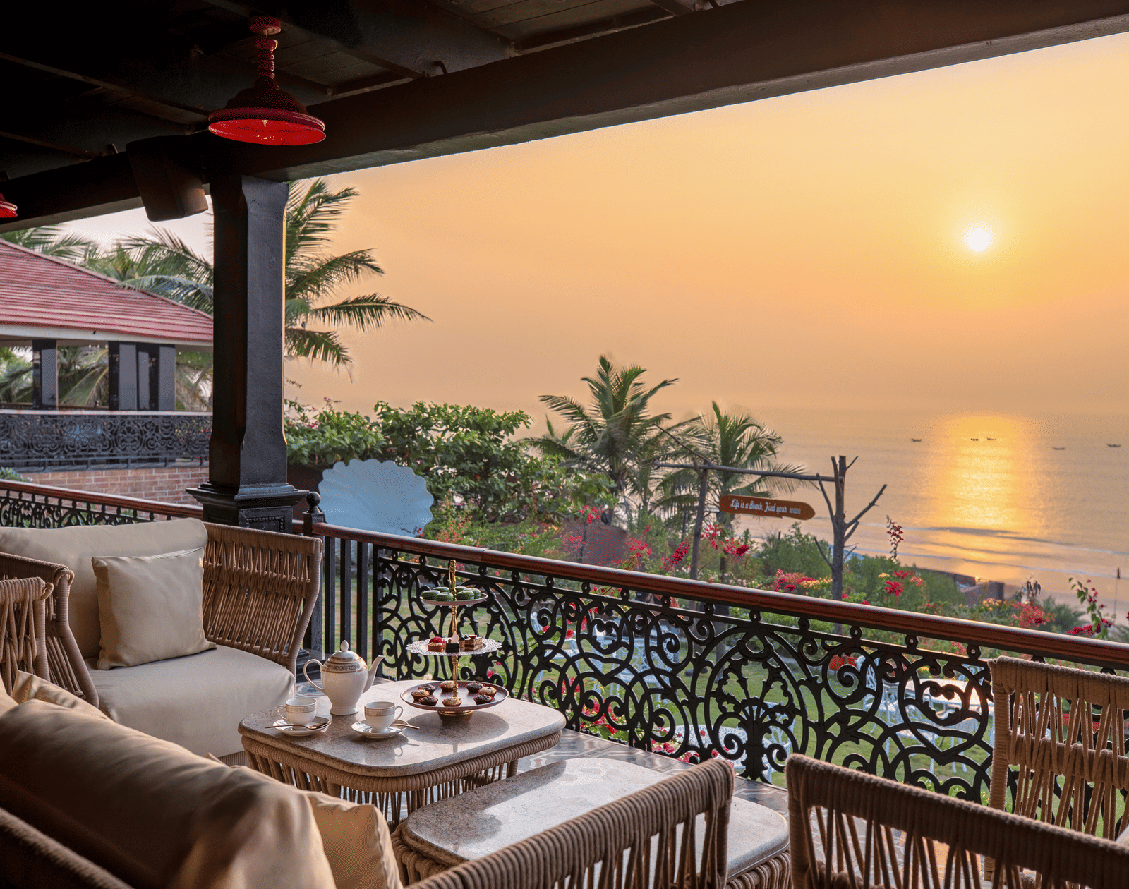 Captain's Deck terrace with wicker sofas, marble tables, an afternoon-tea set and sea beyond the railing at MAYFAIR Palm Beach Resort, Gopalpur-on-Sea.