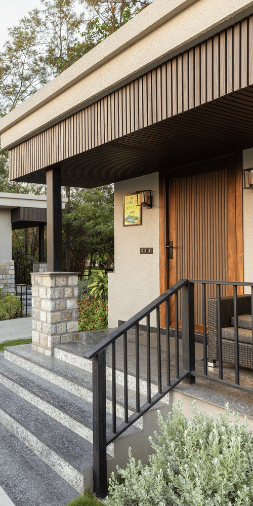 Exterior of jungle spring villa with curved stone pathway leading up to the entrance of a building with stairs and metal railing  at The Golden Tusk, Jim Corbett