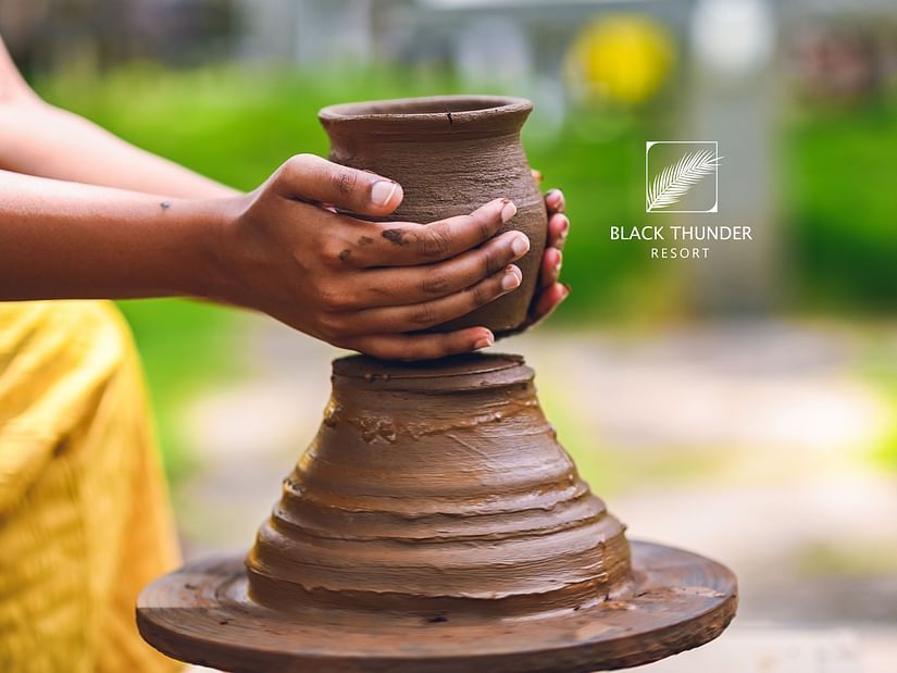 A close-up of hands shaping clay on a potter's wheel, highlighting the creative process of pottery-making - Black Thunder, Coimbatore