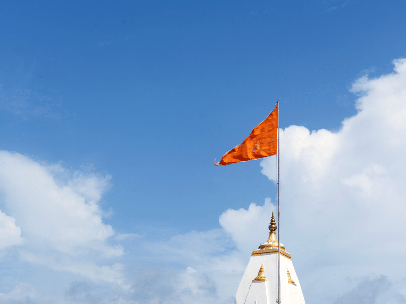 a red flag on top of a white temple with white clouds over the blue sky