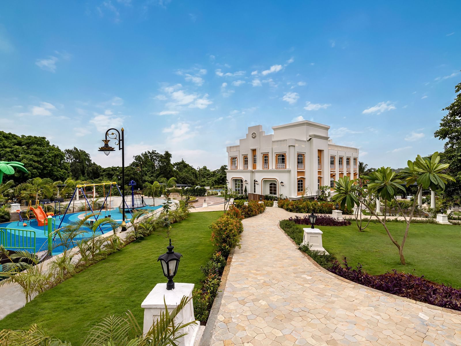 An outdoor play area for kids along side a pathway leading to the facade of Imperial Goa.