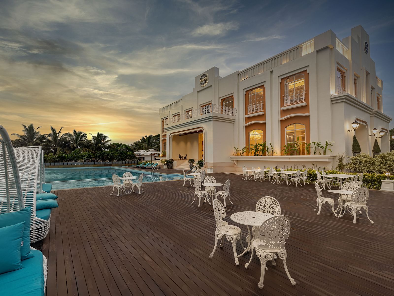 Full view shot of the outdoor dining area featuring the facade of the Imperial Goa overlooking a beautiful sunset in the background.