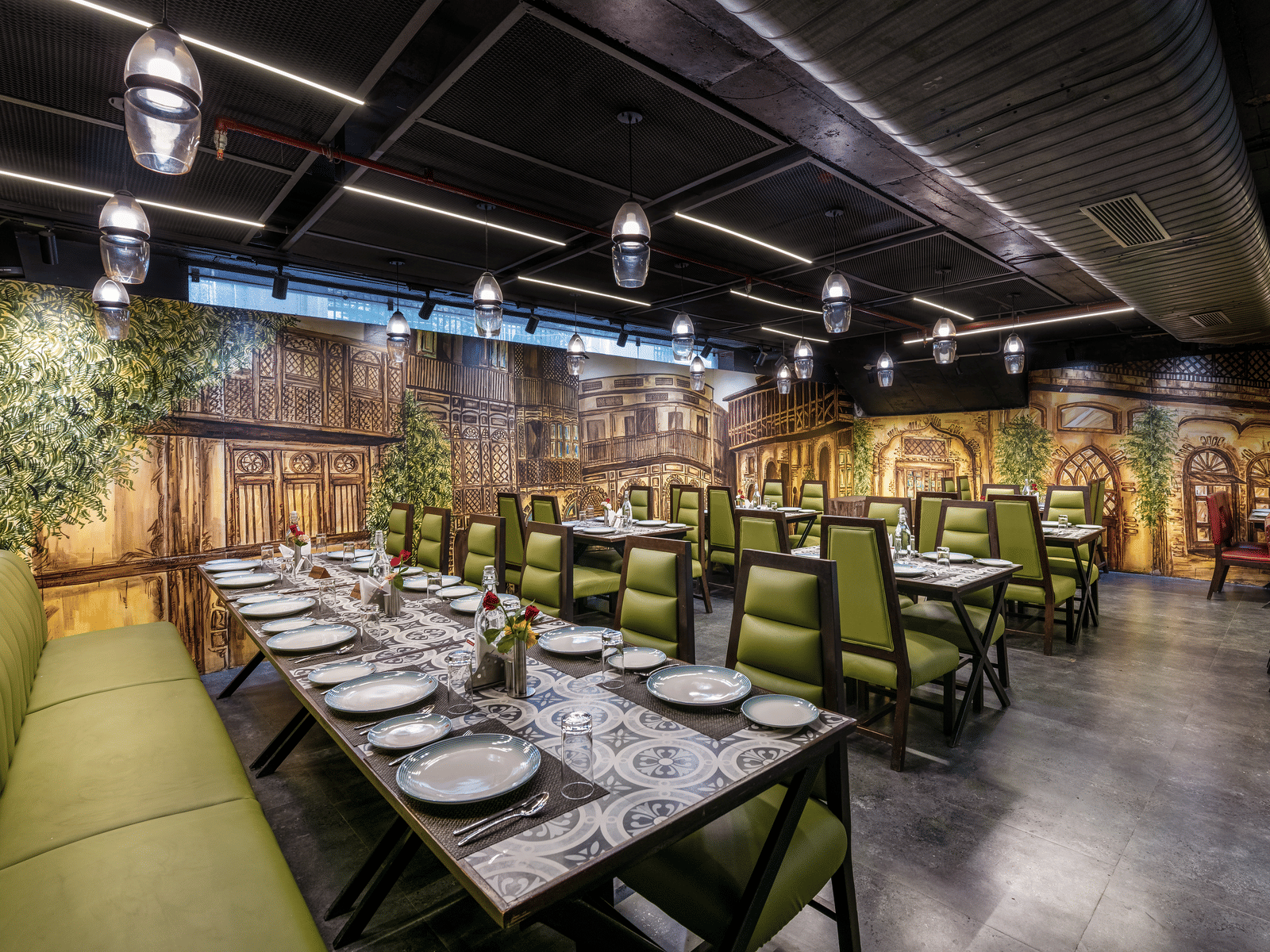 View of a private dining area at Lords Inn Amritsar with green chairs, long dining table, decorative wall murals, and warm ambient lighting.