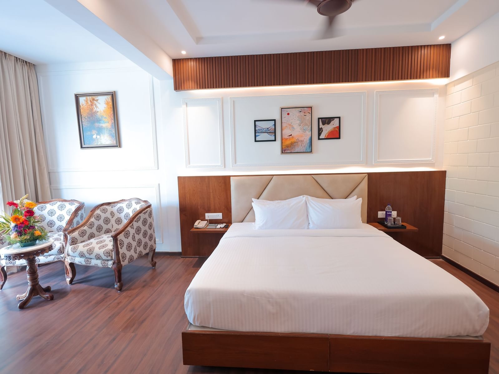 Neatly arranged bedroom with twin chairs and wall art at Trishvam Symphony, Krishnagiri.