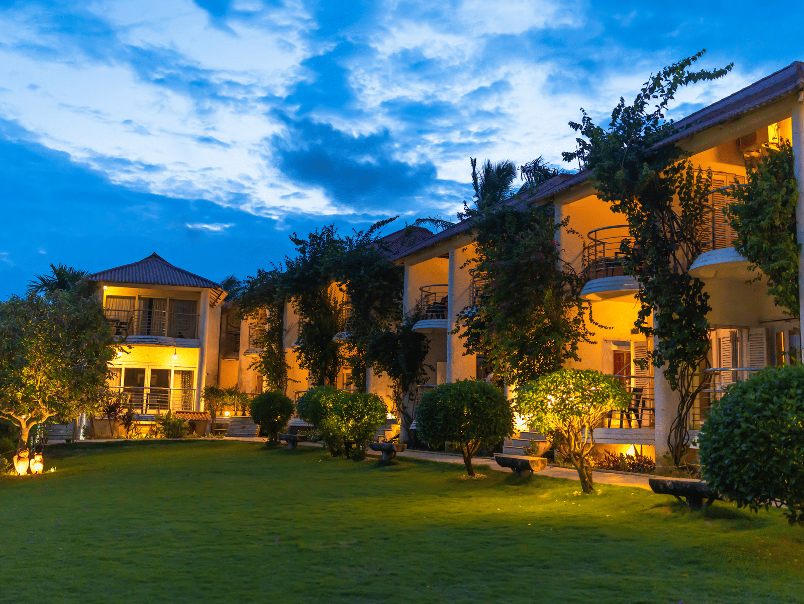 Two-storey hotel complex illuminated at dusk with ivy-covered walls and a green lawn - Hotel Seagull Digha