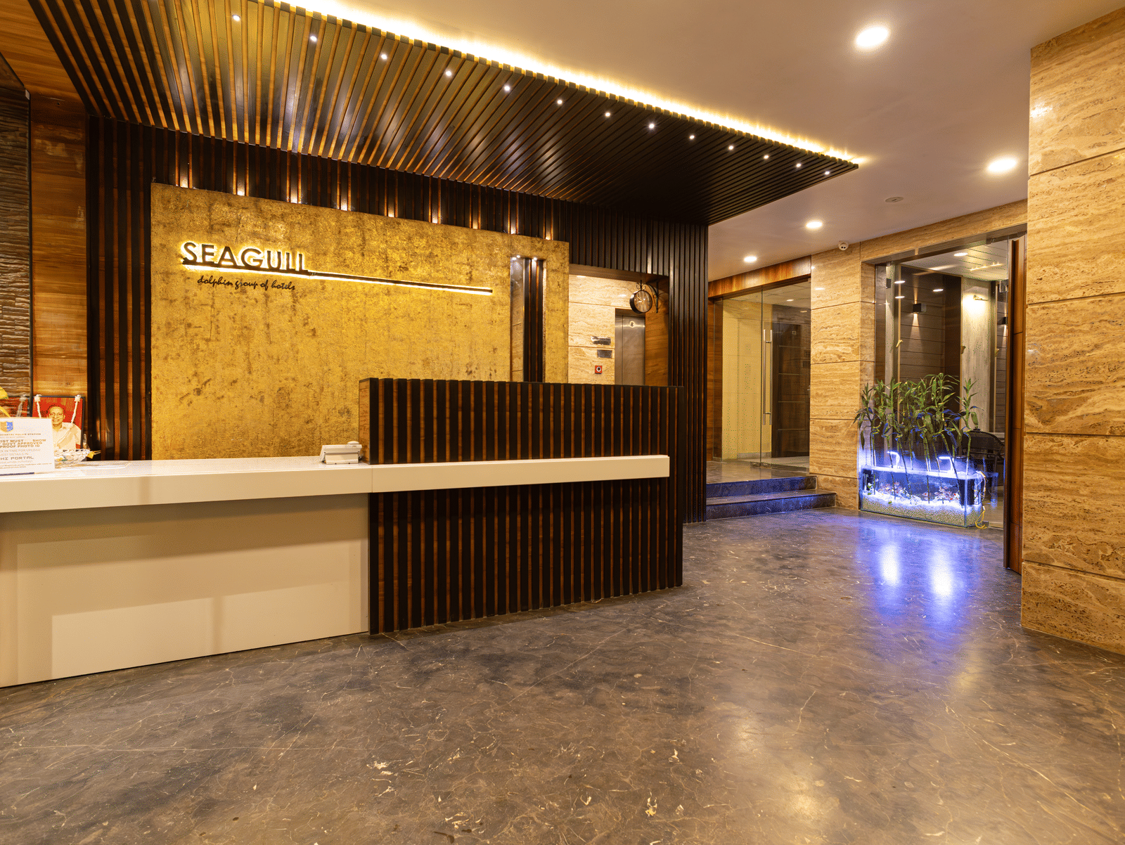 A reception area with front desk, seating space, ceiling lights, and wall decor at Hotel Seagull Digha.