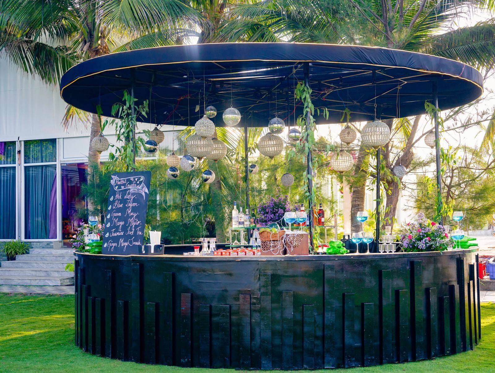 An outdoor bar decorated with flowers with green trees at the back at Grande Bay Resort & Spa.