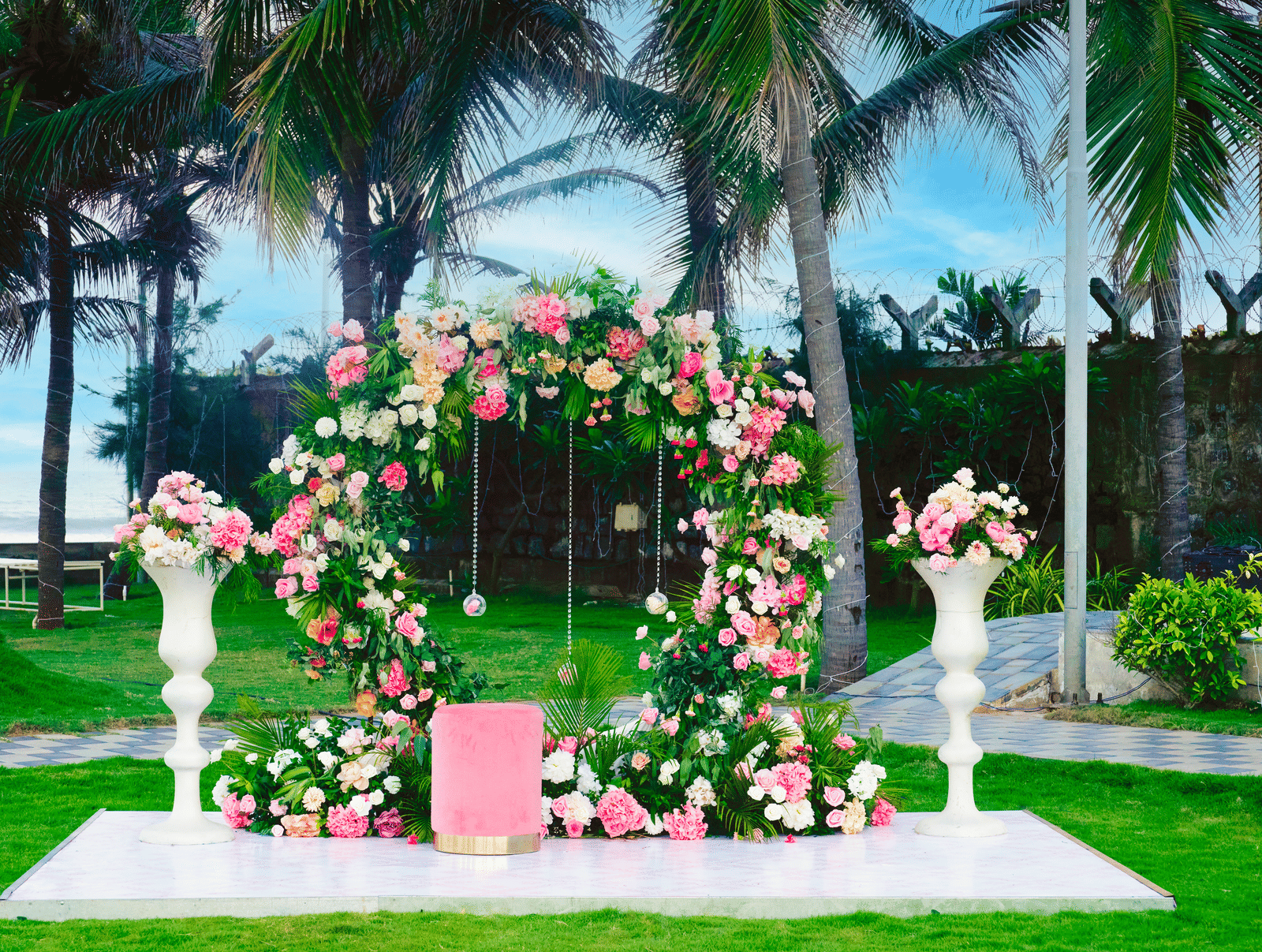 Elegant circular floral ring backdrop with pedestal arrangements on the lawn - Grande Bay Resort & Spa, Mamallapuram