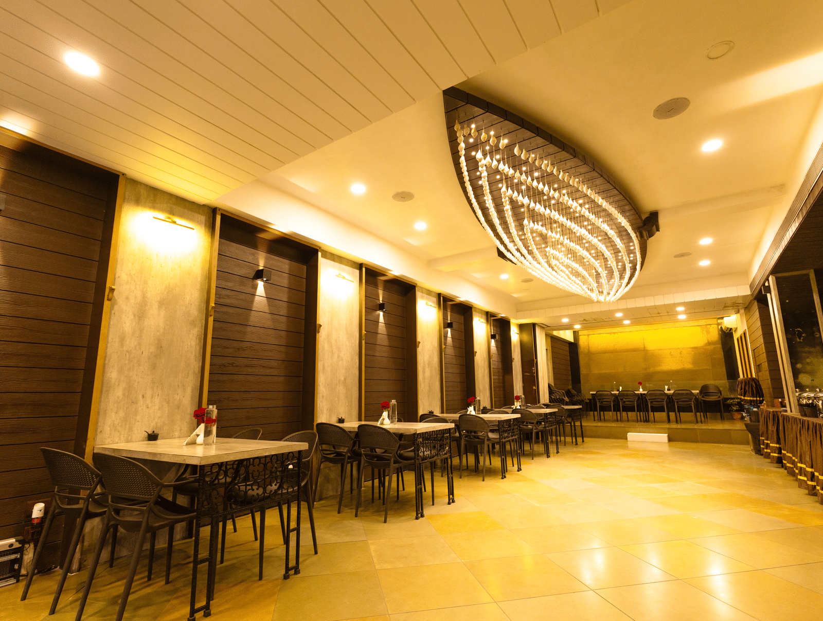 An indoor dining area with dining tables, chairs, and ceiling lights at Hotel Seagull Digha.