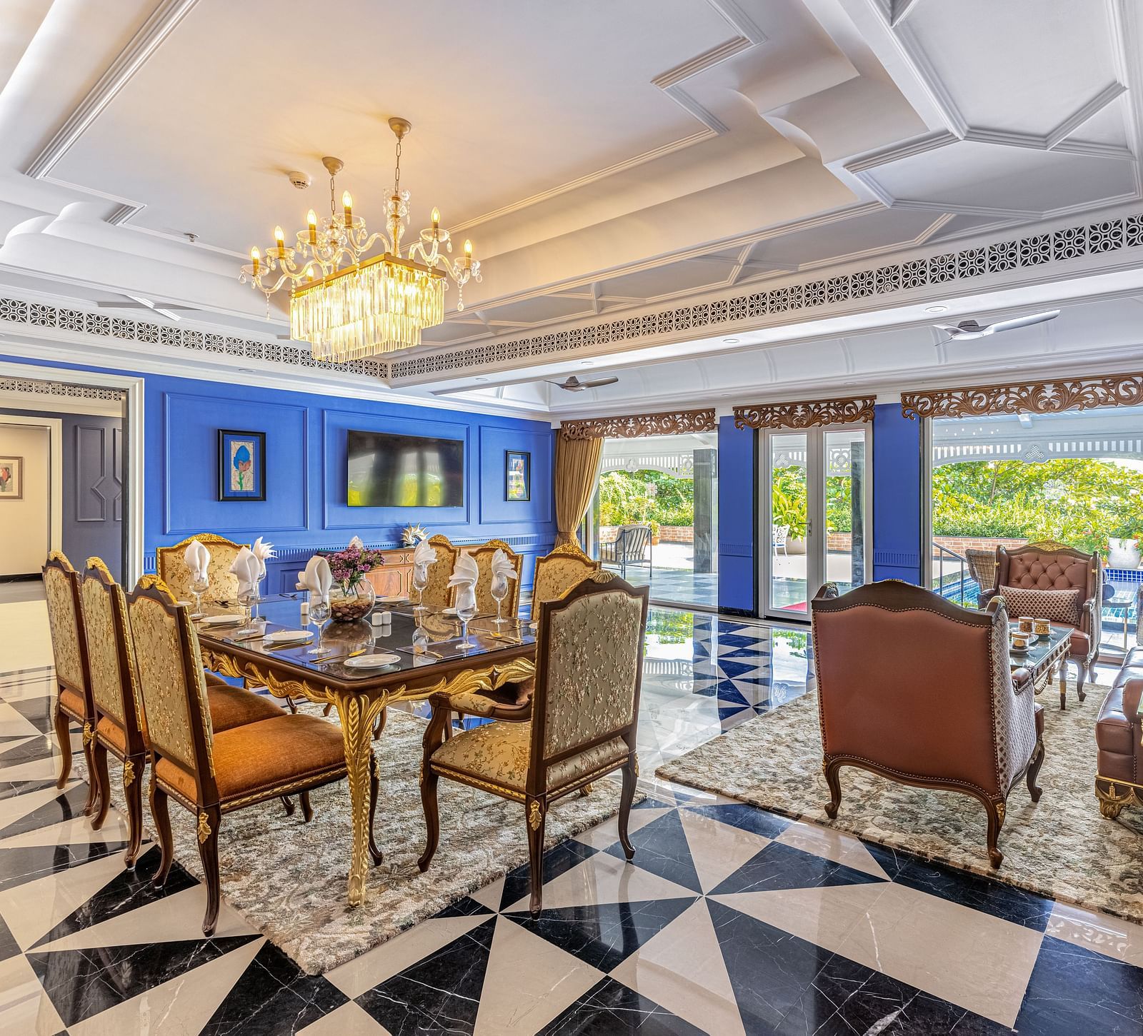 Luxurious dining and lounge area with royal blue walls, ornate chandelier, black-and-white checkered floor, and elegant furniture at MAYFAIR Palm Beach Resort, Gopalpur-On-Sea