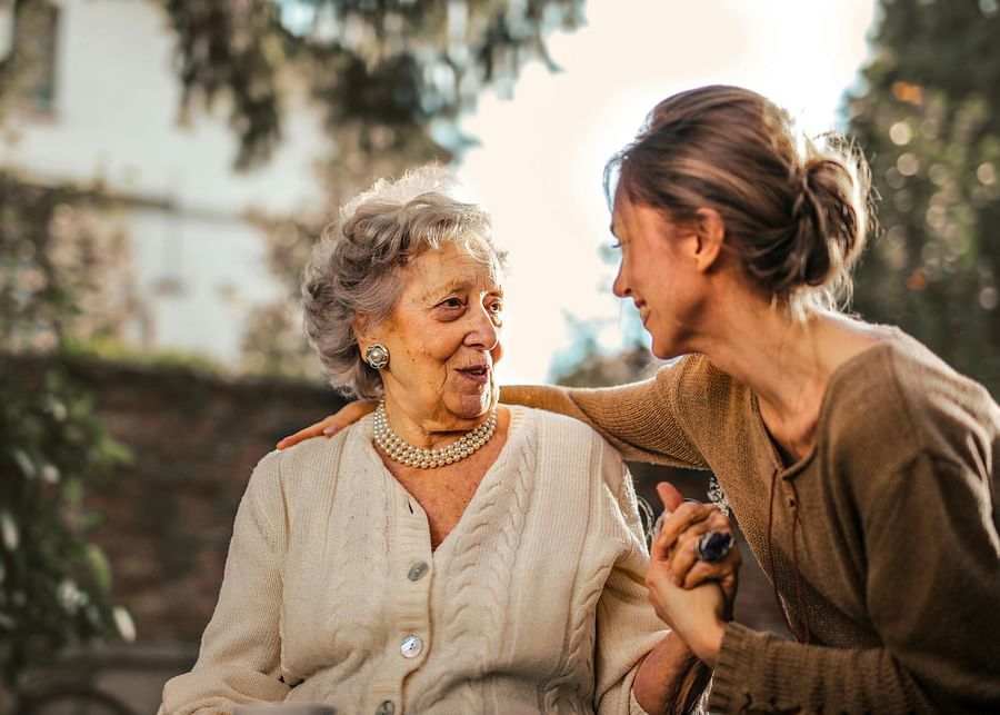 alt-text A photo showing a young girl affectionately spending time with a senior citizen at the golden hour.