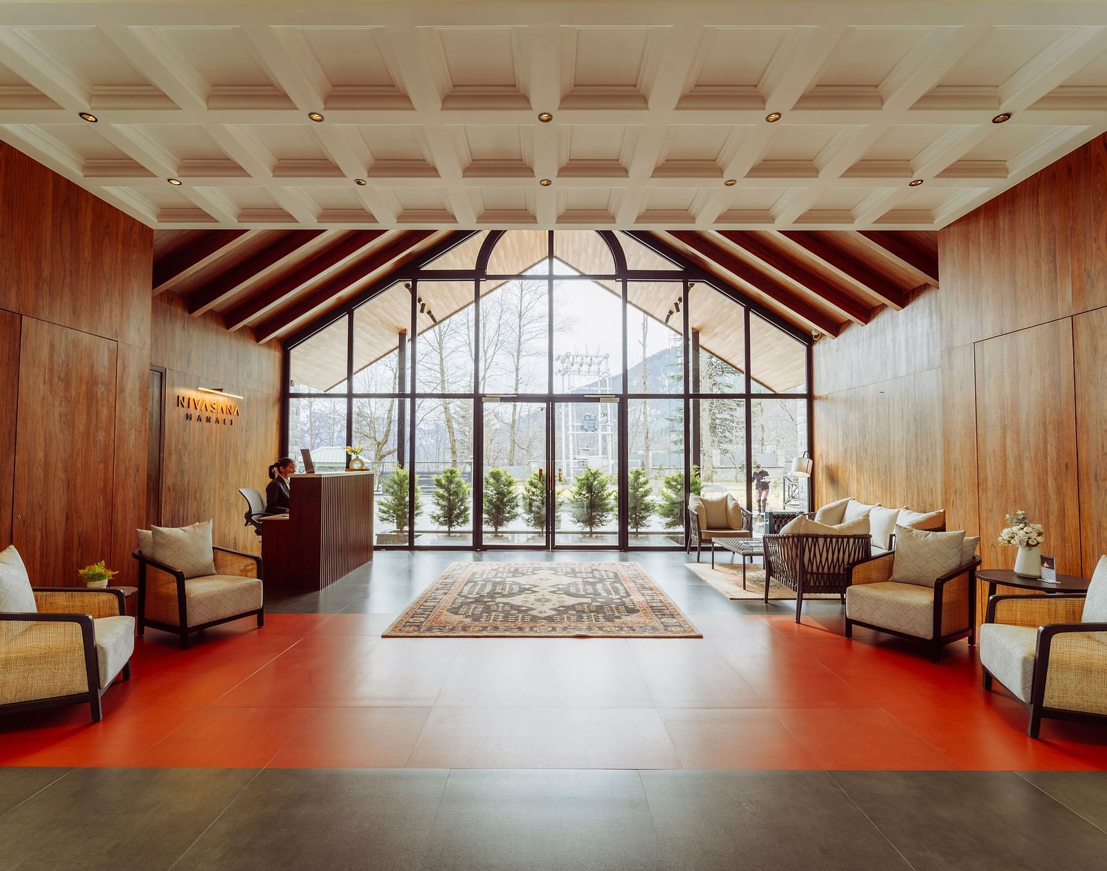 Spacious lounge area with warm lighting, cushioned seating and floor-to-ceiling windows at Nivasana Manali.