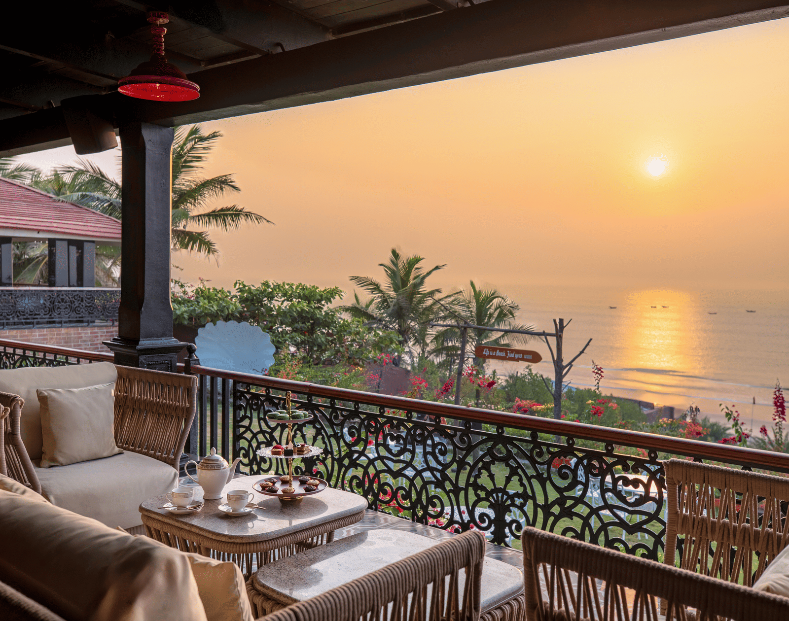 Captain's Deck terrace with wicker sofas, marble tables, an afternoon-tea set and sea beyond the railing at MAYFAIR Palm Beach Resort, Gopalpur-on-Sea.