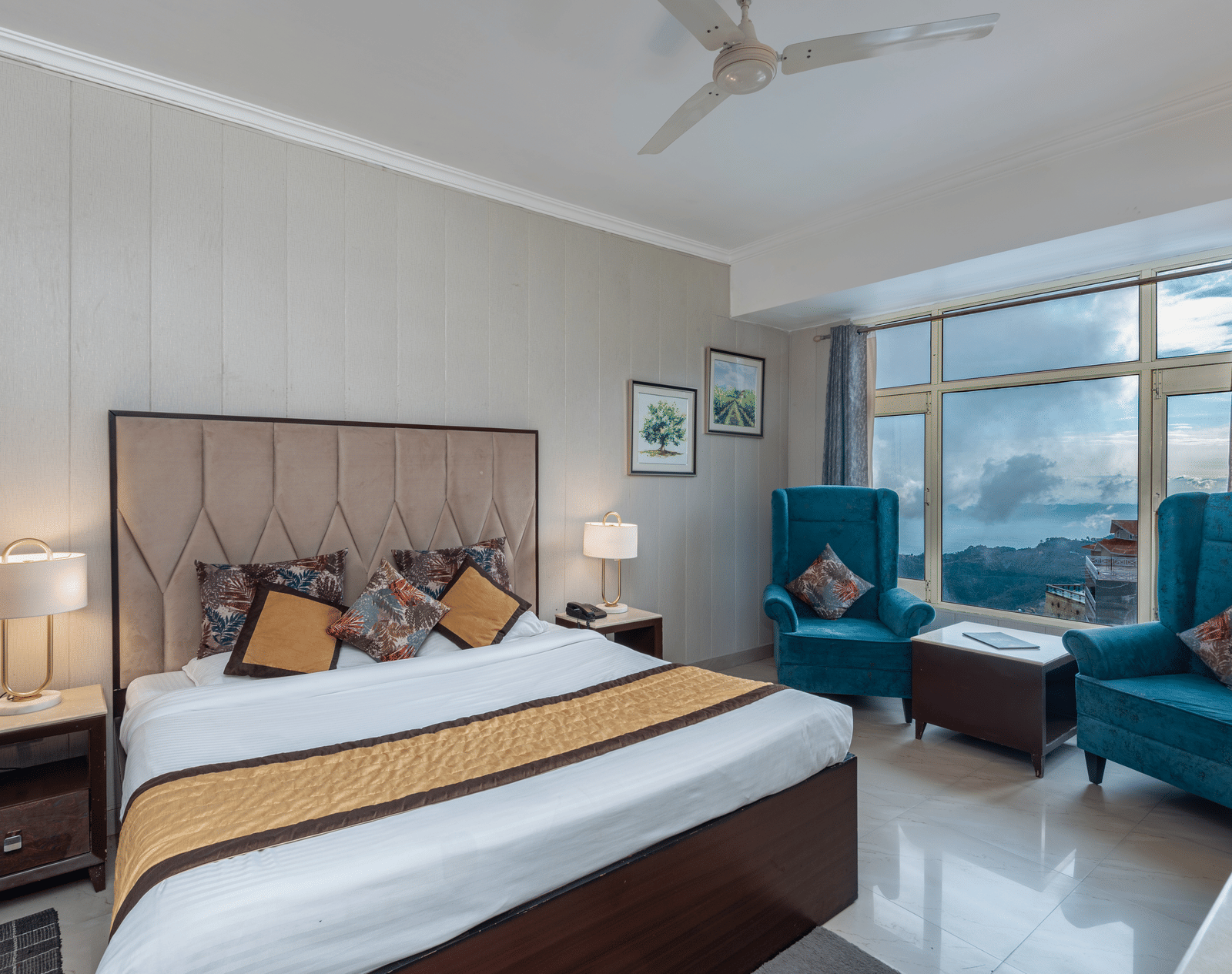 Shot on a well furnished room featuring a king size bed and a large window with two chairs placed near the window | DLS The Pearl