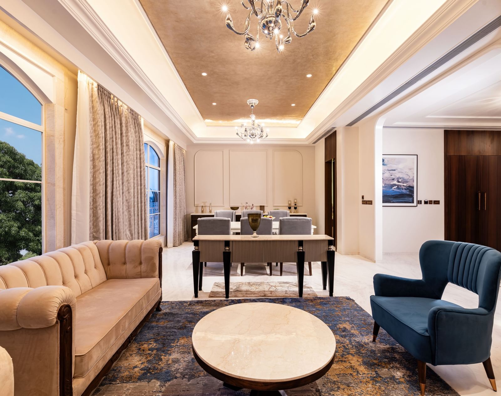 The common seating area with an arm chair facing towards the huge white cushioned couch at the Suite at Imperial Goa.