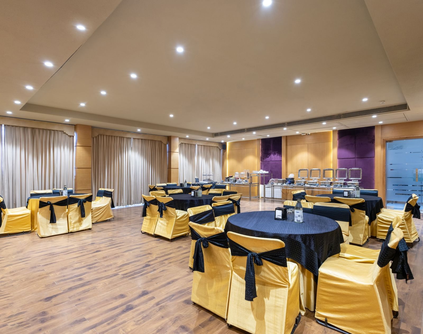 Banquet hall, Iris, with tables in cluster seating arrangment, wooden flooring, seen at Pravasa Stay Vijay Nagar, Indore.