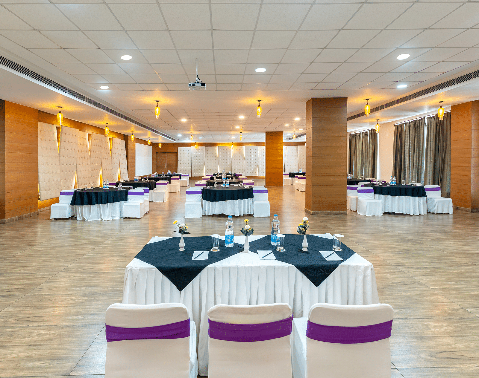 A larger empty event hall with white tables and chairs - Via Lakhela Resort & Spa