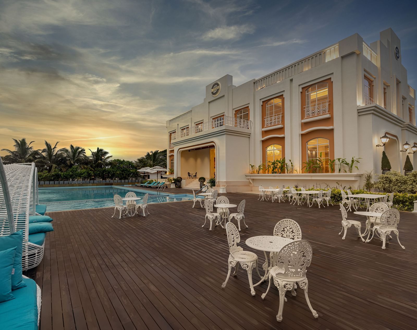 Full view shot of the outdoor dining area featuring the facade of the Imperial Goa overlooking a beautiful sunset in the background.