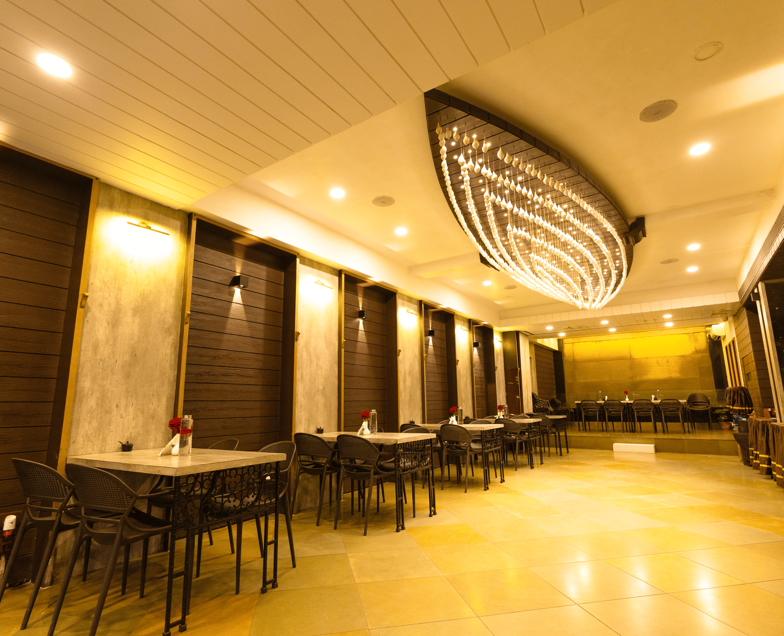 An indoor dining area with dining tables, chairs, and ceiling lights at Hotel Seagull Digha.