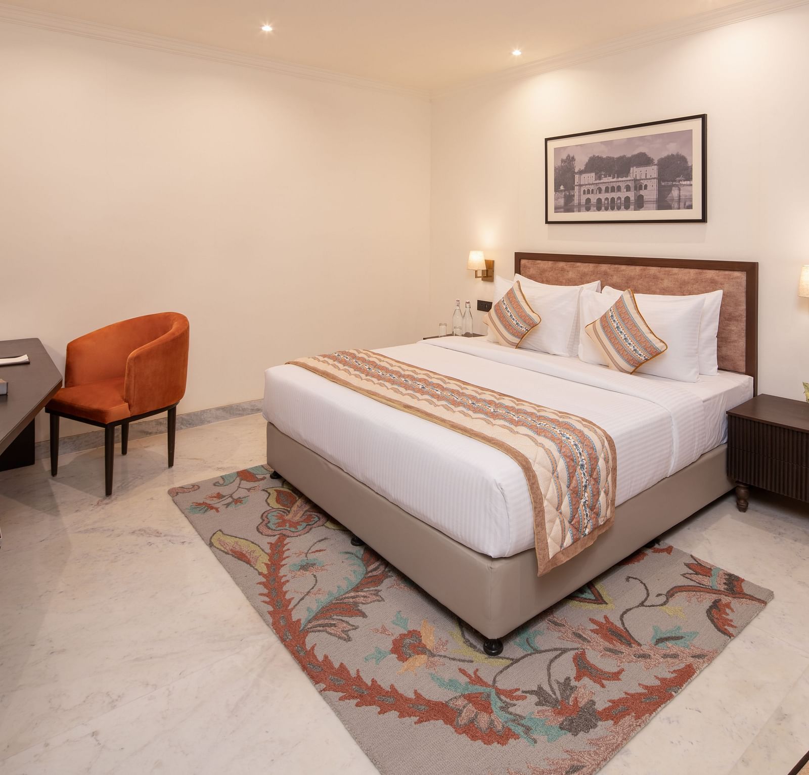 An image of a bedroom with bedside table, photo frame hanged on the wall, work desk with sofa chair, and a flat TV screen - Brij Eternity, Vrindavan