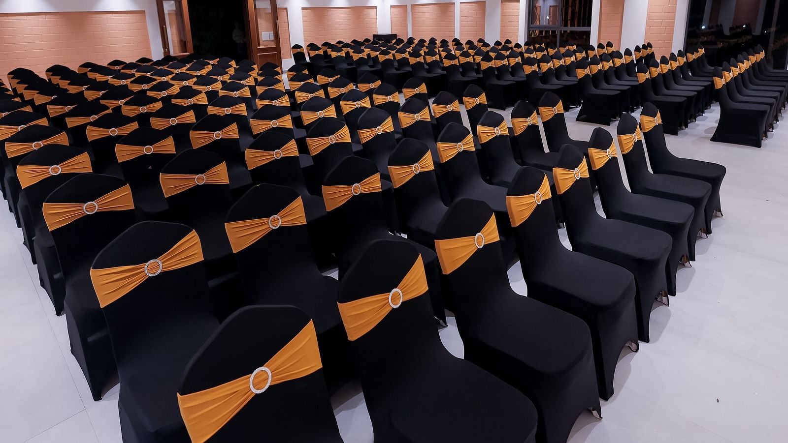 Conference hall at Trishvam Symphony, Krishnagiri, set up with rows of cushioned chairs for seminars or presentations.