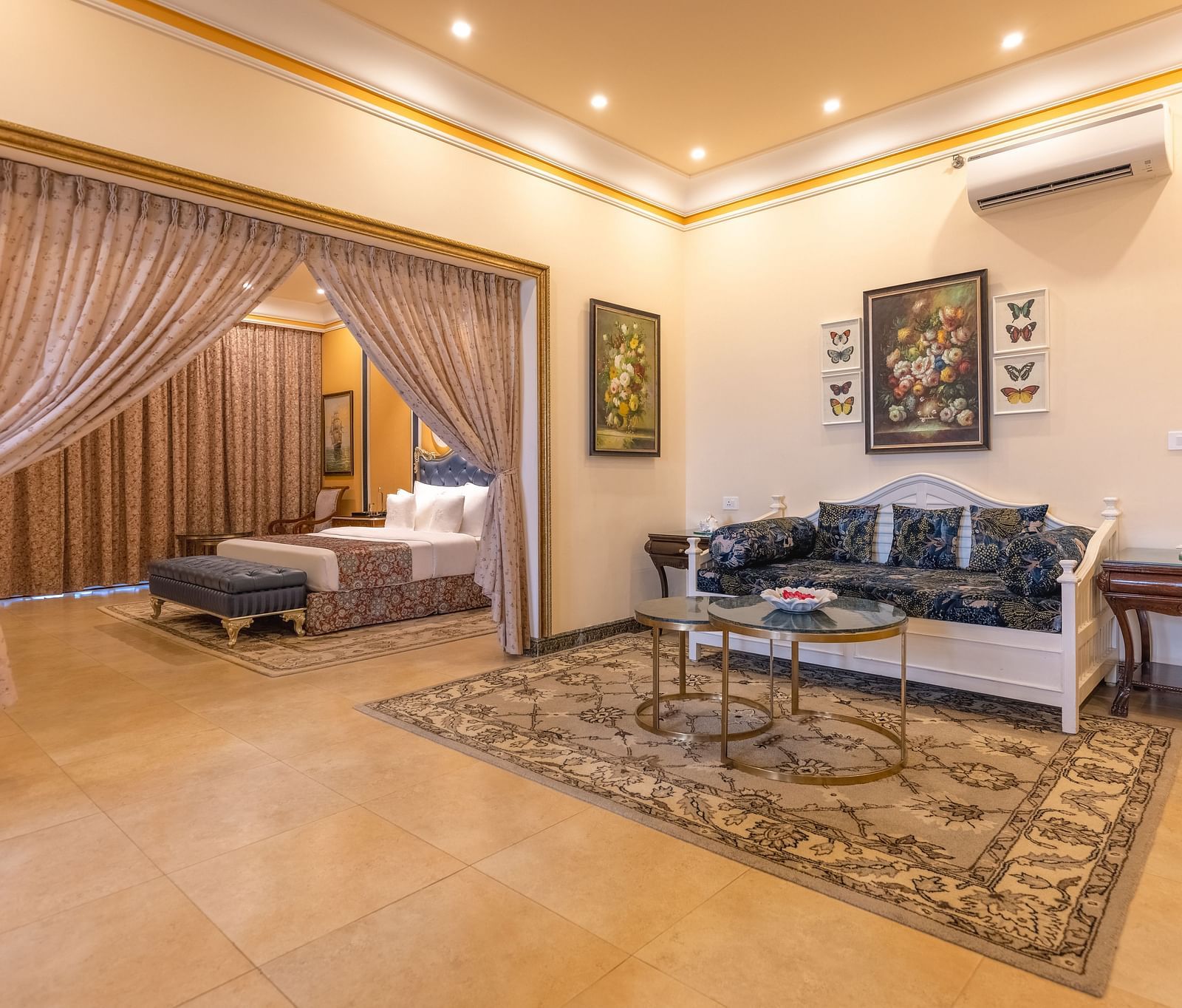 A double bedroom, with a separate living space with sofa and a coffee table and a wall-mounted air-conditioner at MAYFAIR Palm Beach Resort, Gopalpur-On-Sea