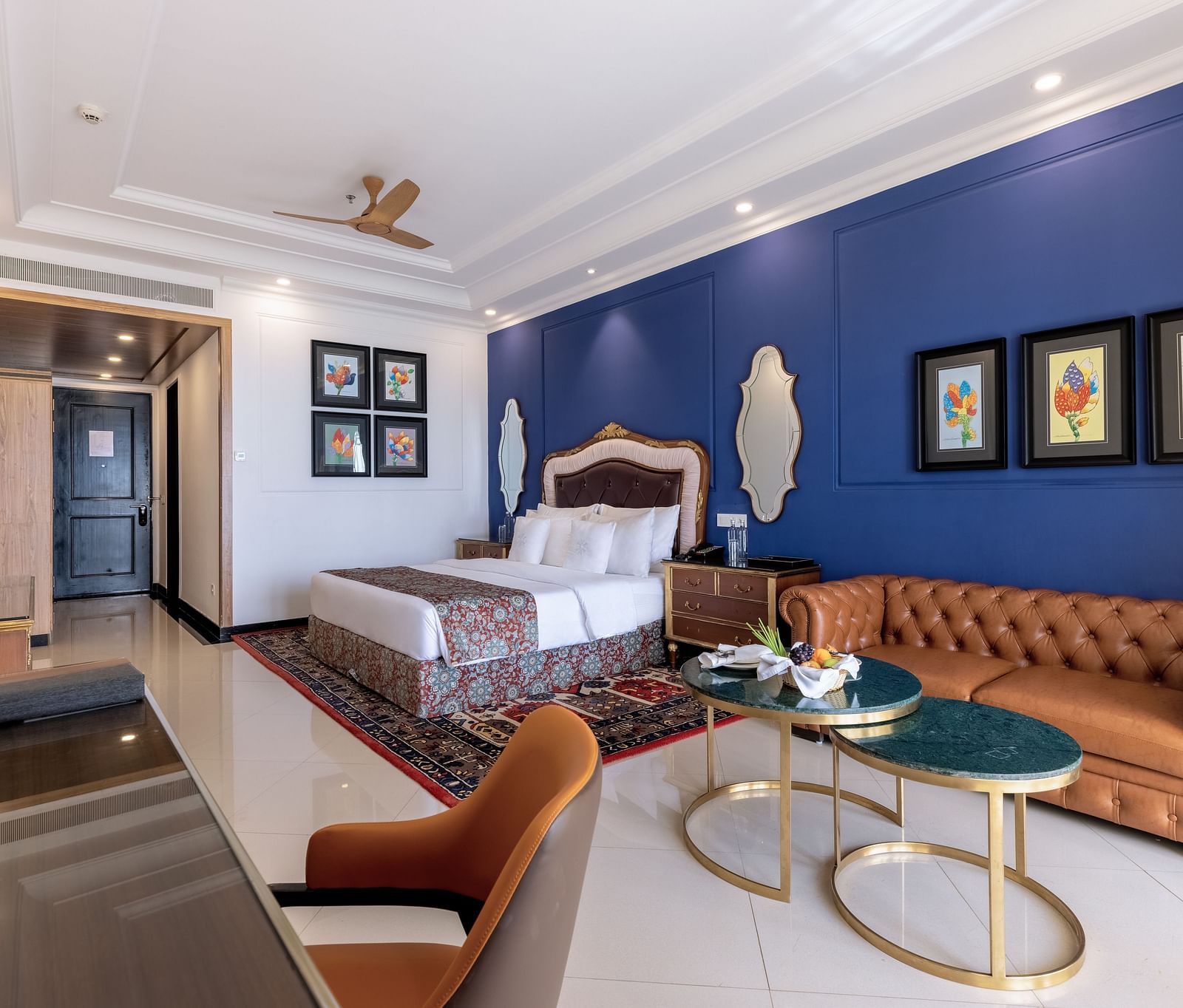 Double bed room with seating area, a workstation, a ceiling fan, and a wall-mounted TV at MAYFAIR Palm Beach Resort, Gopalpur-On-Sea