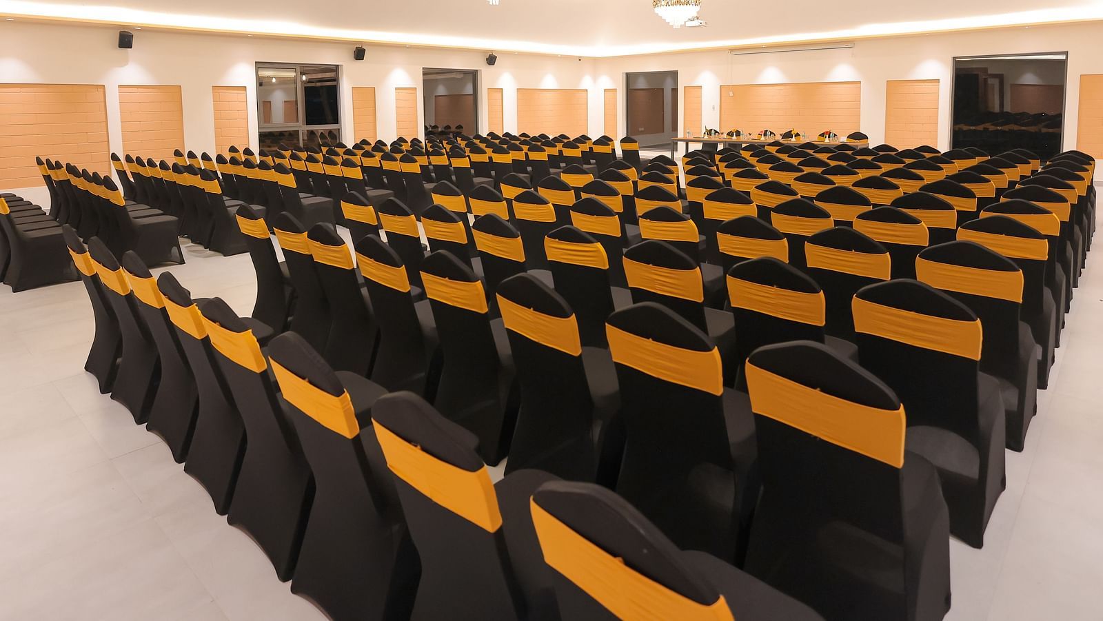 Spacious seminar hall at Trishvam Symphony, Krishnagiri, with black and yellow cushioned chairs arranged theatre-style.