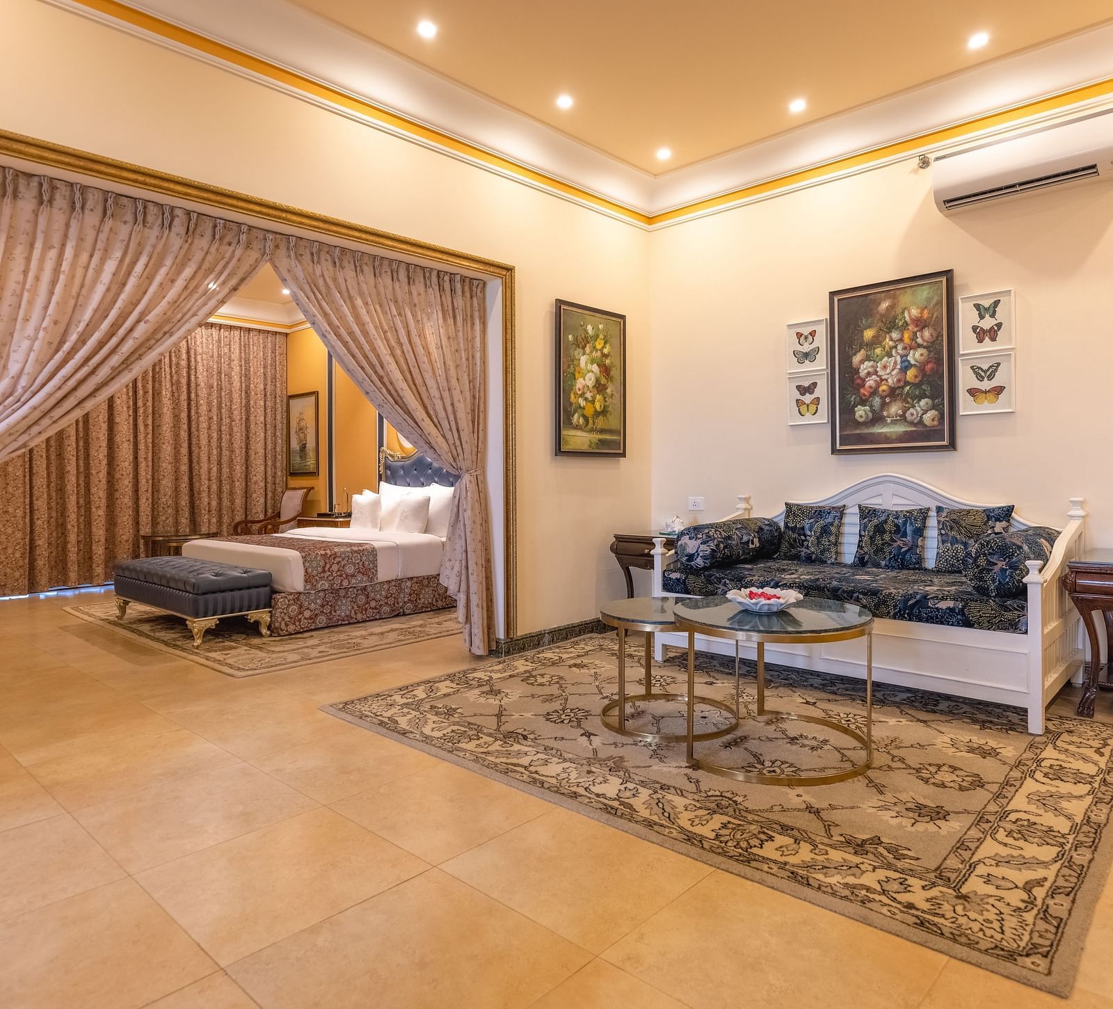 A double bedroom, with a separate living space with sofa and a coffee table and a wall-mounted air-conditioner at MAYFAIR Palm Beach Resort, Gopalpur-On-Sea