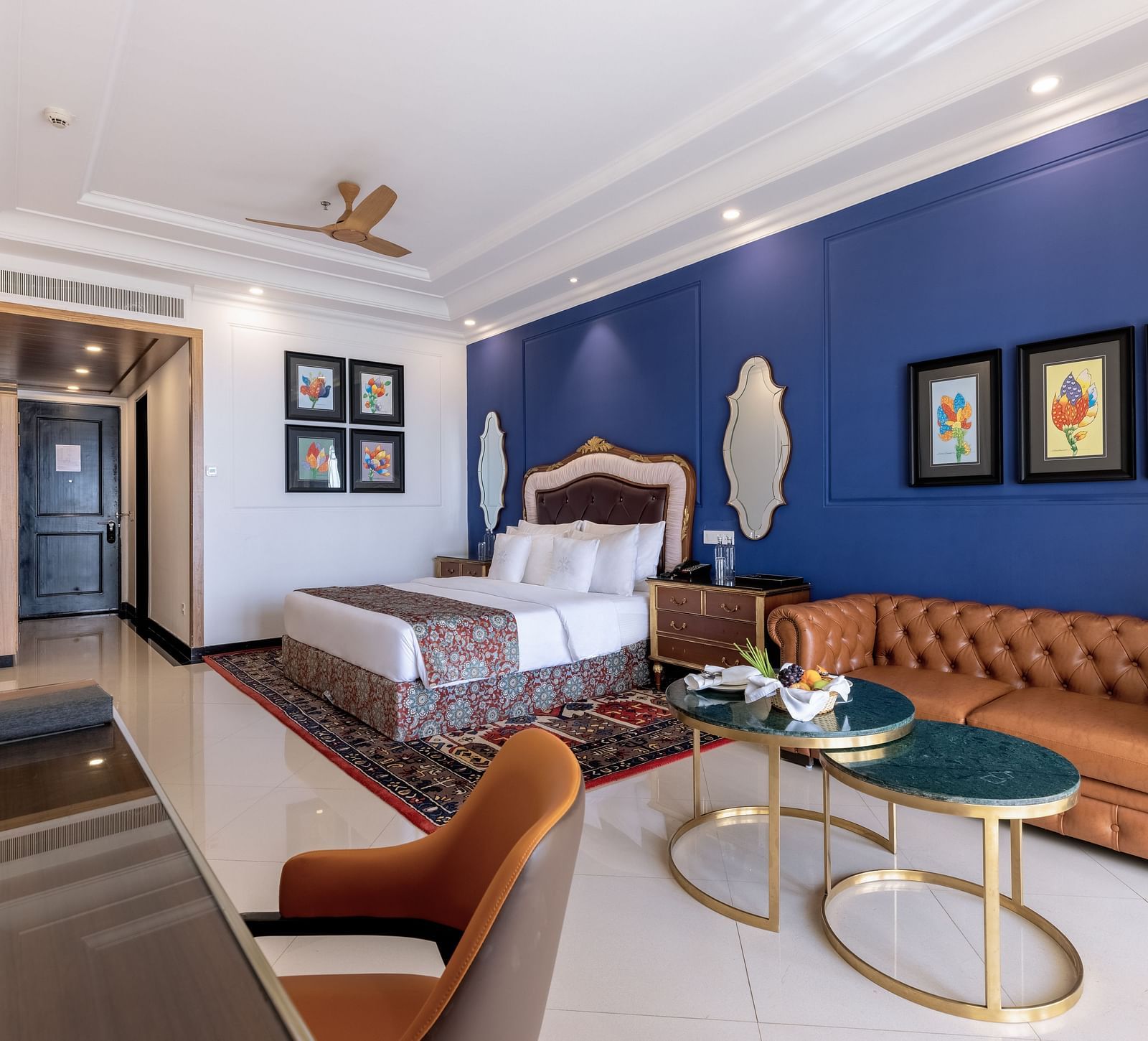 Double bed room with seating area, a workstation, a ceiling fan, and a wall-mounted TV at MAYFAIR Palm Beach Resort, Gopalpur-On-Sea