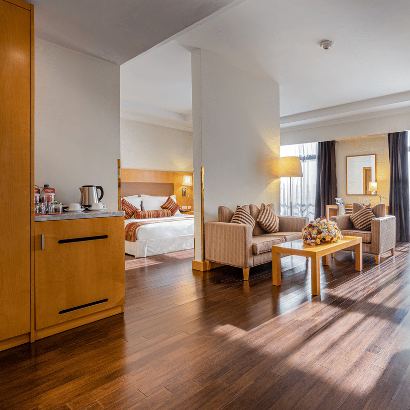 A bedroom having a king size bed with the living room in the foreground having sofas and a coffee table at the Executive Suite in Ramada by Wyndham Addis, a 4-star hotel in Addis Ababa
