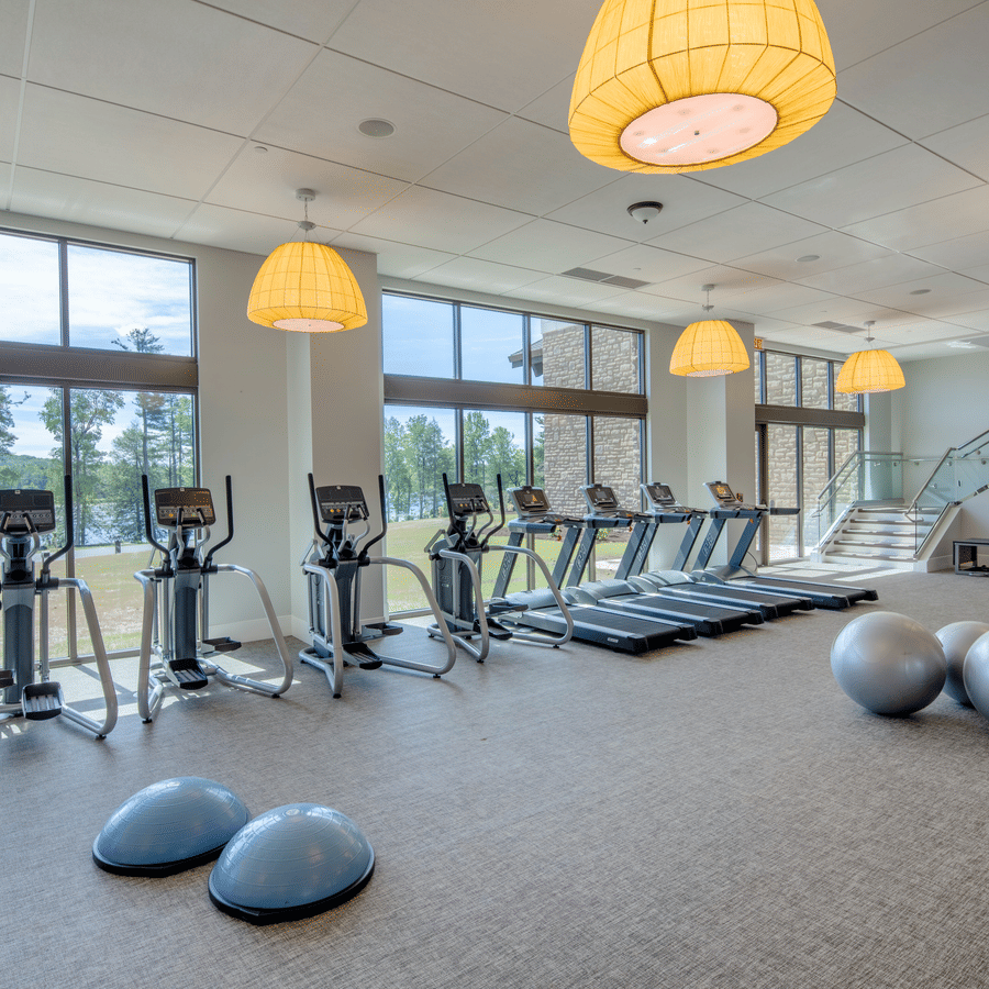Modern fitness center at YO1 with large windows, cardio machines, exercise balls, and natural lighting.